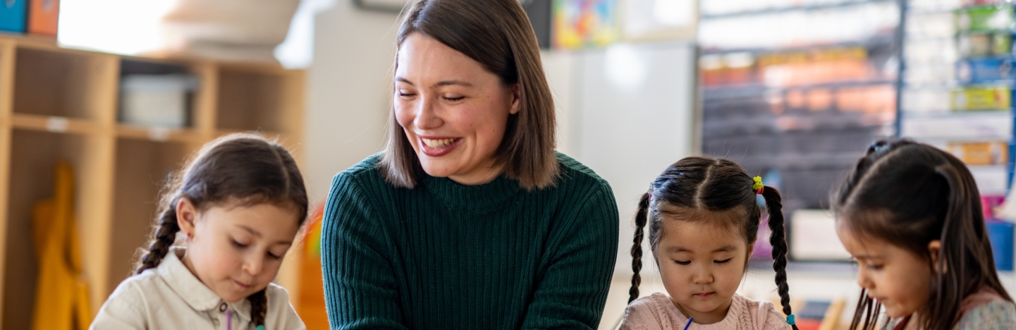 A teacher sits with a small group of young students