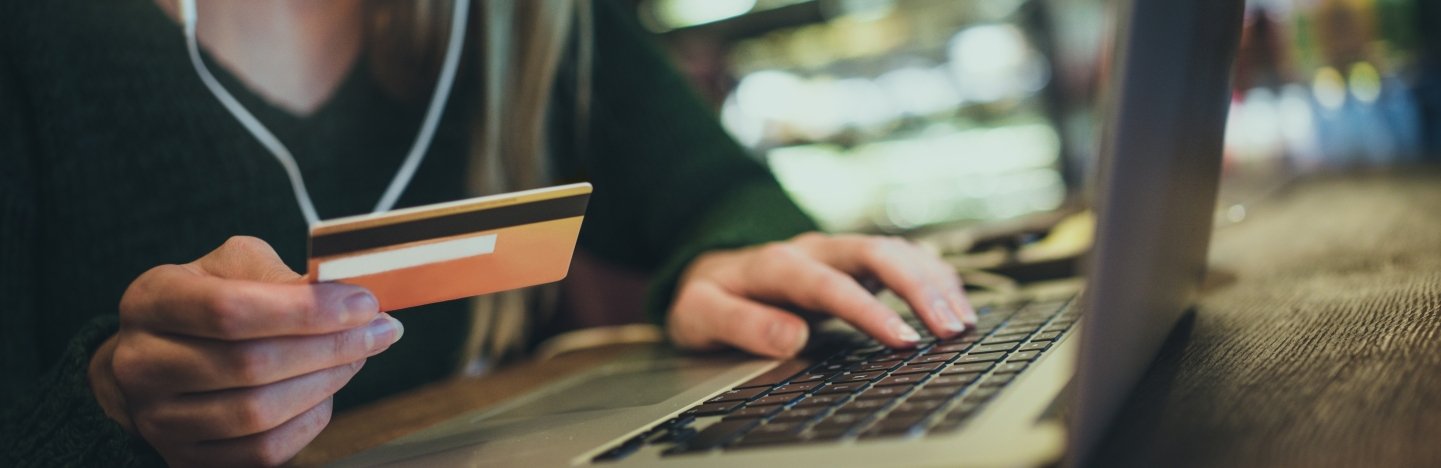 A woman types her credit card information into a laptop computer