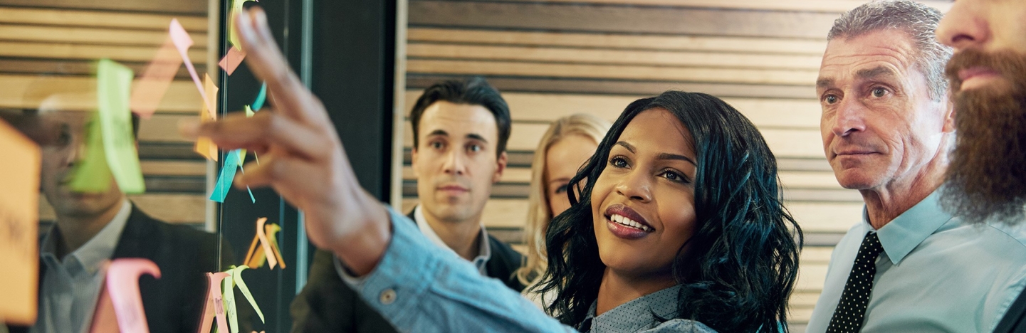 A group of people gather around a board to collaborate