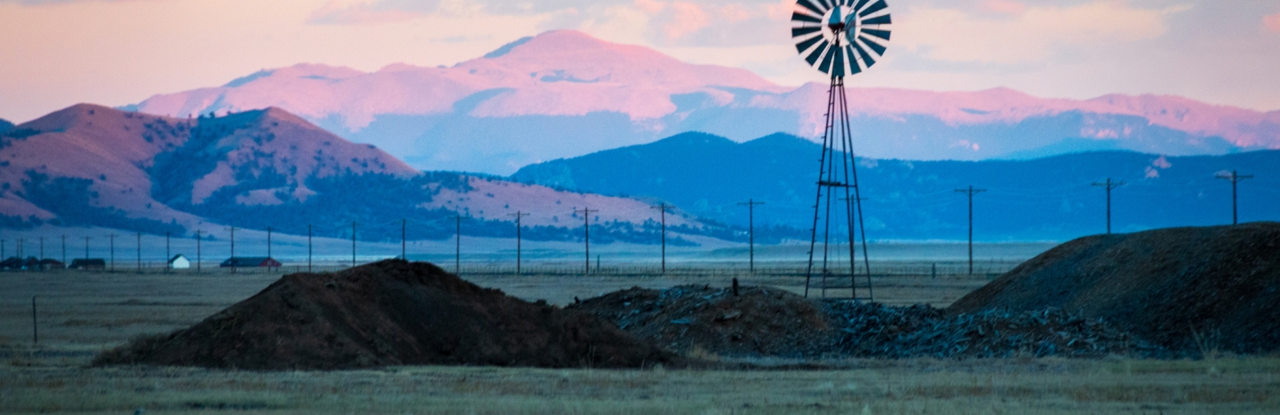 Wind Turbines On Land Against Pikes Peak And Sky During Sunset