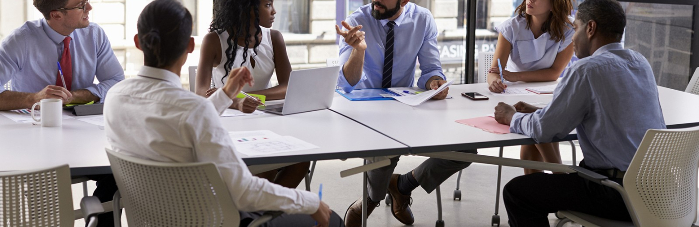 Office workers sit around a table for a meeting