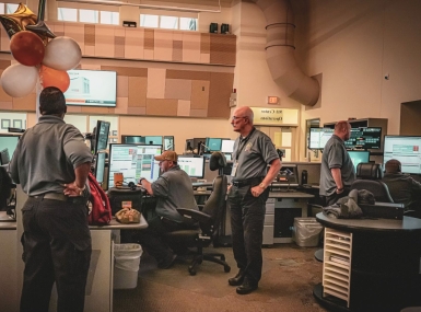 John Farrell (center) ignores the balloons and gets to work on his 50th anniversary with the New Castle County 911 Communications department. Photo courtesy of New Castle County