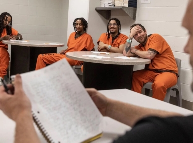 Hennepin County inmates listen as a FreeWriters participant shares his writing with them.