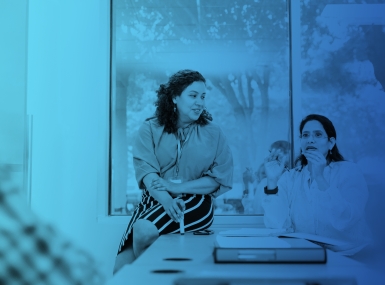 two women talk in a conference room 