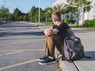 Teenager sitting on curb