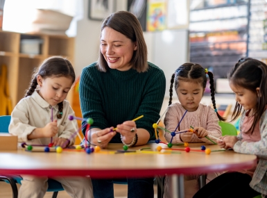A teacher sits with a small group of young students