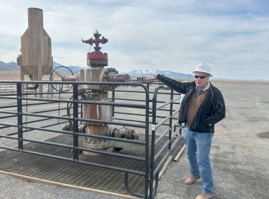 John McLennan shows off a geothermal wellhead on the Utah FORGE site in Beaver County, Utah. Photo by Charlie Ban