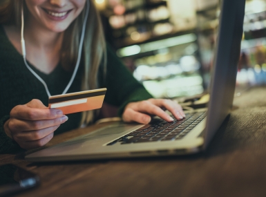 A woman types her credit card information into a laptop computer