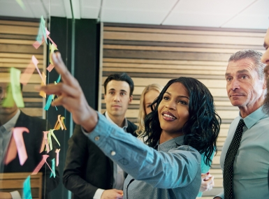 A group of people gather around a board to collaborate