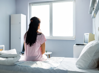 Anxious, sad, young woman wearing hospital gown