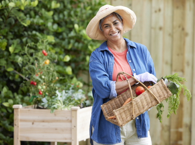 Lady standing in her garden with a basket of vegetables 