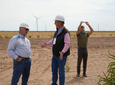 Carson County, Texas Judge Dan Looten (center) talks to Hodgeman County, Kan. Commissioner Mike Schraeder about wind power during a visit to the Panhandle Wind Project Development in Carson County. To the right, El Paso County, Texas Senior Policy Analyst Ramon Bracamontes take a photo of a nearby wind turbine. Photo by Charlie Ban