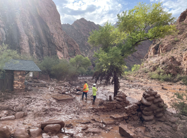 Two people stand among debris at near a footbridge that was destroyed in Grand Canyon National Park Aug. 29 during a flash flood earlier in the day. Photo courtesy of the National Park Service