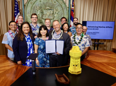 Economic Recovery Corps Fellow George Yarbrough (back row, center) poses during a bill signing with Hawaii Gov. Josh Green (holding the bill).