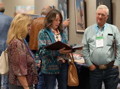 New Mexico Counties Executive Director Joy Esparsen (left) huddles with Roosevelt County Commissioner Tina Dixon and her husband Durward, who will succeed her in January, at the NACo Energy Symposium. Photo by Charlie Ban