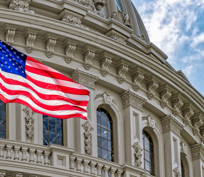 The American flag waves in front of the US Capitol Building