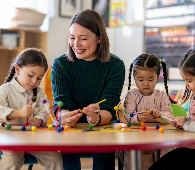 A teacher sits with a small group of young students