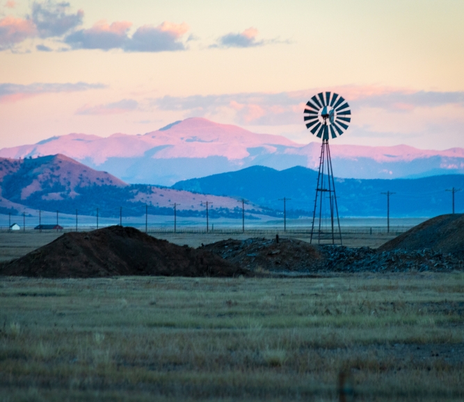 Wind Turbines On Land Against Pikes Peak And Sky During Sunset