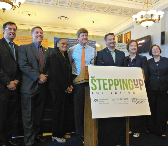(L-r): Council of State Governments Excecutive Director Michael Thompson; Loudoun County, Va. Sheriff Mike Chapman; Ramsey County, Minn. Commissioner Toni Carter; Rep. Patrick Kennedy (D-Mass.); mental health advocate Paton Blough; NACo Strategic Relations Director Linda Langston and Department of Justice Director of Justice Assistance Denise O'Donnell celebrate the launch of the Stepping Up Initiative in May 2015. Langston, a former Linn County, Iowa supervisor, was a NACo president. Photo by Alix Kashdan