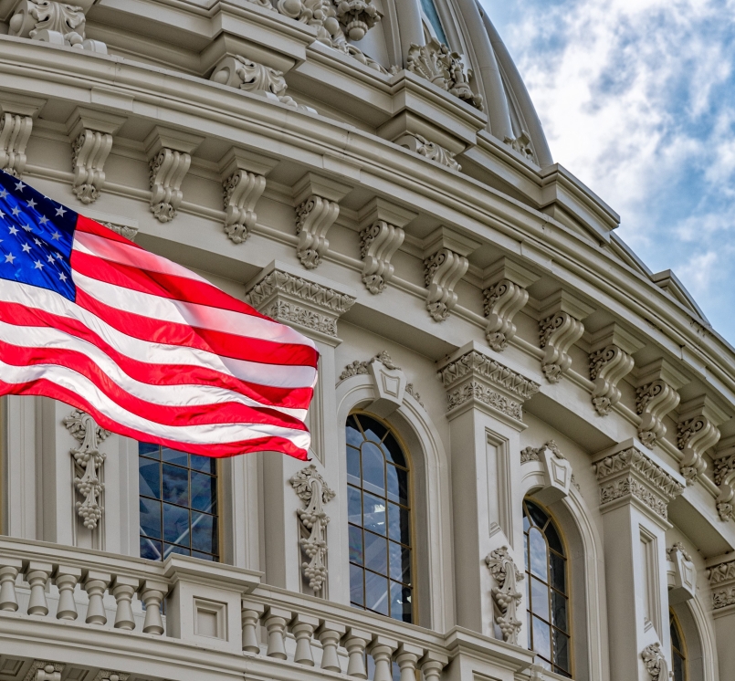 The American flag waves in front of the US Capitol Building