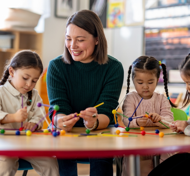 A teacher sits with a small group of young students