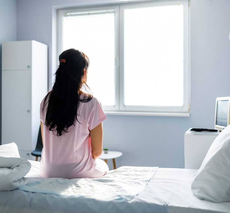 Anxious, sad, young woman wearing hospital gown