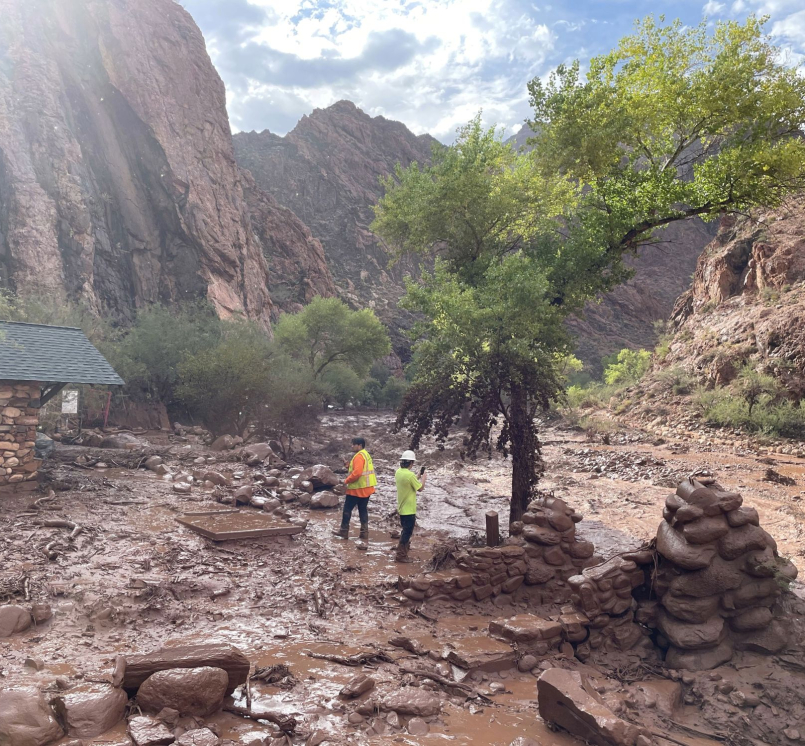 Two people stand among debris at near a footbridge that was destroyed in Grand Canyon National Park Aug. 29 during a flash flood earlier in the day. Photo courtesy of the National Park Service