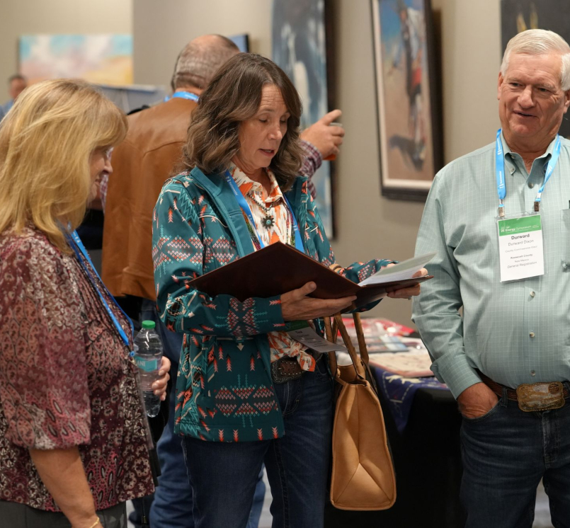 New Mexico Counties Executive Director Joy Esparsen (left) huddles with Roosevelt County Commissioner Tina Dixon and her husband Durward, who will succeed her in January, at the NACo Energy Symposium. Photo by Charlie Ban