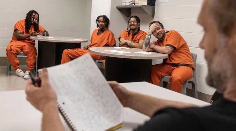 Hennepin County inmates listen as a FreeWriters participant shares his writing with them.