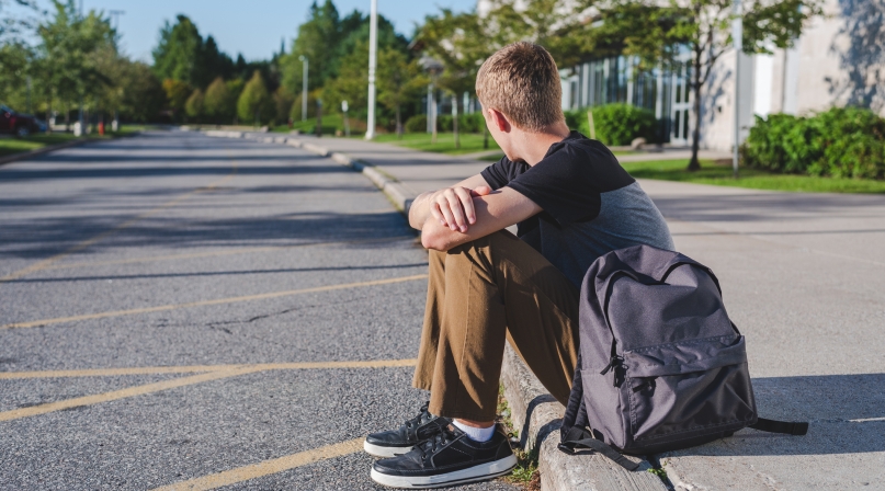 Teenager sitting on curb