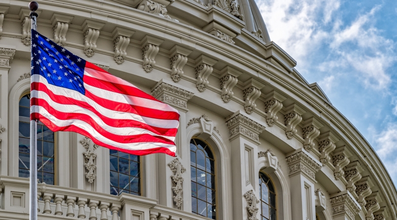 The American flag waves in front of the US Capitol Building