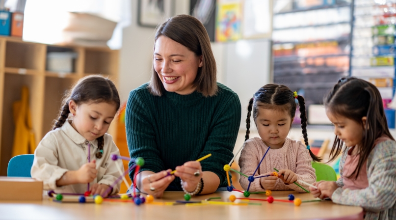 A teacher sits with a small group of young students