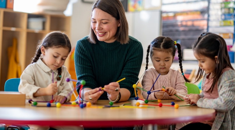 A teacher sits with a small group of young students