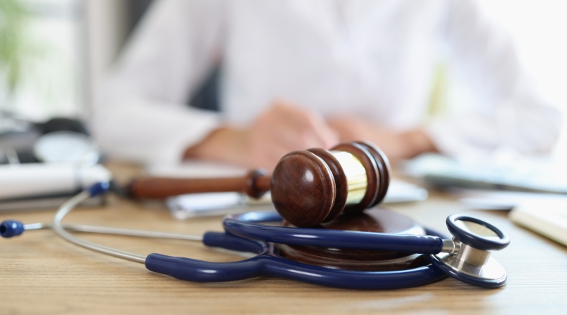 Closeup of judge gavel of stethoscope doctor in background writing notes