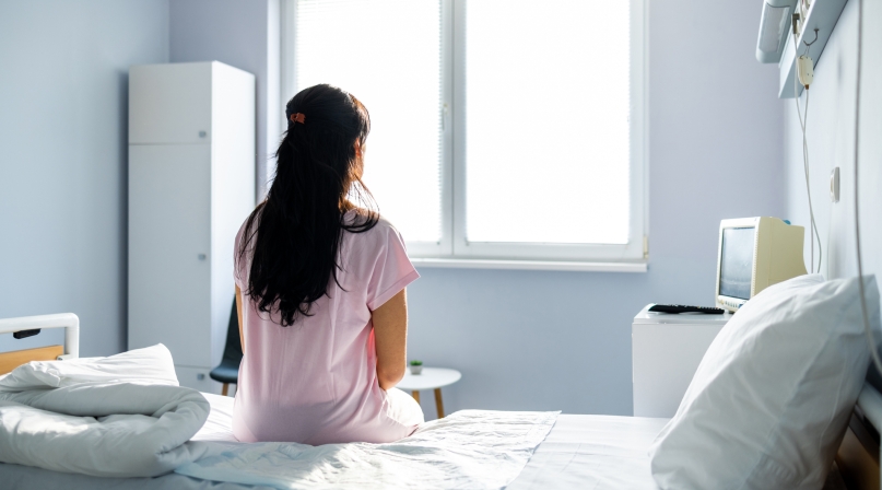 Anxious, sad, young woman wearing hospital gown