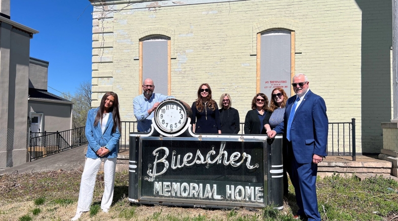 Staff of the Missouri Association of Counties stand in front of the historic “Buescher Memorial Home” sign located at 429 Capitol Ave. in Jefferson City. From left: Intern Isabella Grander, Deputy Director David Owen, Member Engagement Director Carah Bright, Finance and Operations Manager Cindy Wells, Administrative Support Assistant Charlotte Onstott, Event and Marketing Coordinator Meredith Melahn and Executive Director Steve Hobbs. Not pictured due to traveling: Trust Risk Manager Sean McGonigle