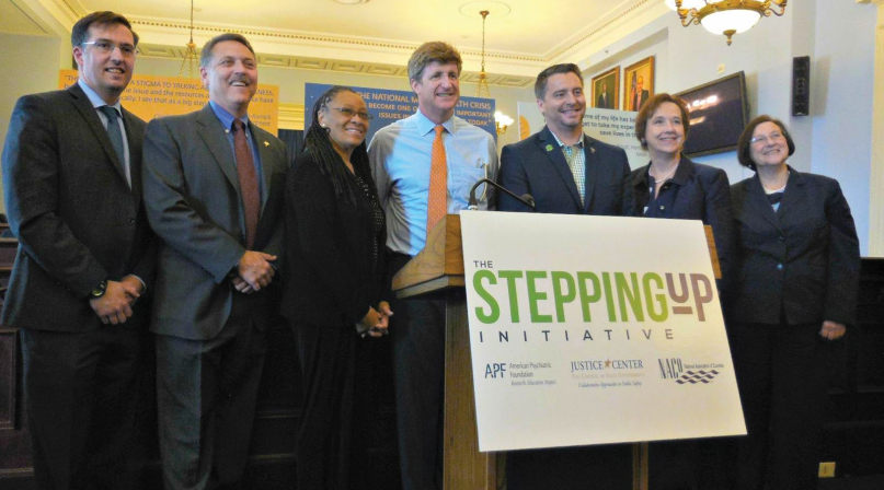 (L-r): Council of State Governments Excecutive Director Michael Thompson; Loudoun County, Va. Sheriff Mike Chapman; Ramsey County, Minn. Commissioner Toni Carter; Rep. Patrick Kennedy (D-Mass.); mental health advocate Paton Blough; NACo Strategic Relations Director Linda Langston and Department of Justice Director of Justice Assistance Denise O'Donnell celebrate the launch of the Stepping Up Initiative in May 2015. Langston, a former Linn County, Iowa supervisor, was a NACo president. Photo by Alix Kashdan