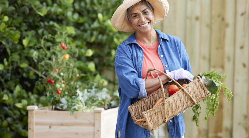 Lady standing in her garden with a basket of vegetables 