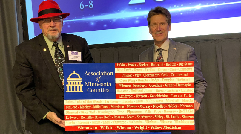 Blue Earth County Commissioner Vance Stuehrenberg presents Lake County Commissioner Rich Sve with a flag in honor of Sve's term as Association of Minnesota Counties president. 