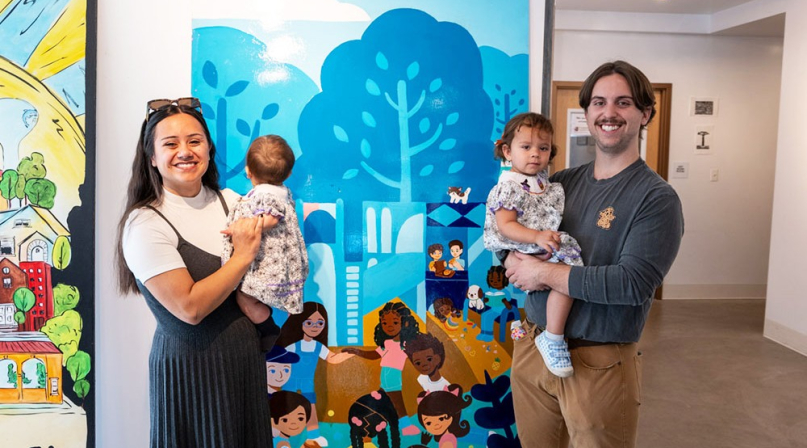 Vivian Piña, one of Brookfield Shops’ featured artists, poses with her family in front of the panel she created of Kiwanis Park. The funding was made possible through the county’s Creative Placemaking grant.