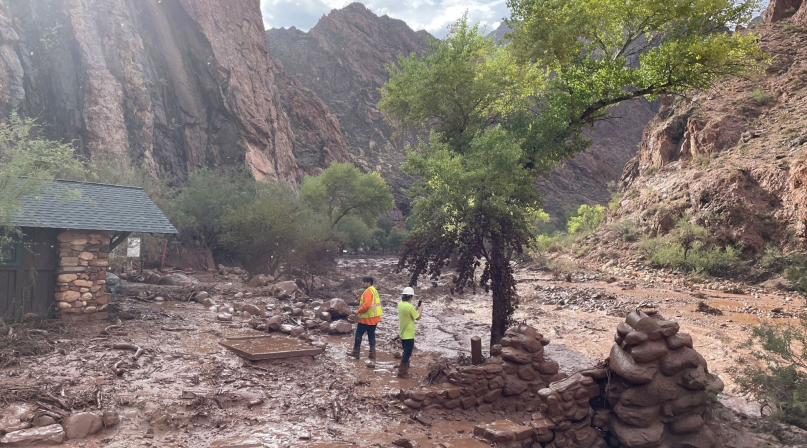Two people stand among debris at near a footbridge that was destroyed in Grand Canyon National Park Aug. 29 during a flash flood earlier in the day. Photo courtesy of the National Park Service