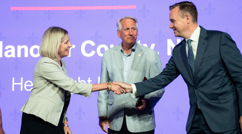 NACo President J.D. Clark congratulates New Hanover County, N.C. Chief Strategy Officer Jennifer Rigby and Commissioner Rob Zapple on the county's Best in Category Civic Eduacation Achievement Award for the Help Right Here program. Photo by Denny Henry