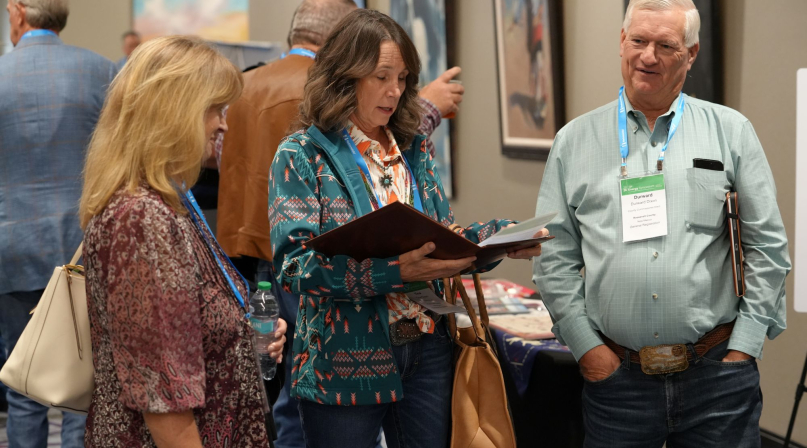 New Mexico Counties Executive Director Joy Esparsen (left) huddles with Roosevelt County Commissioner Tina Dixon and her husband Durward, who will succeed her in January, at the NACo Energy Symposium. Photo by Charlie Ban