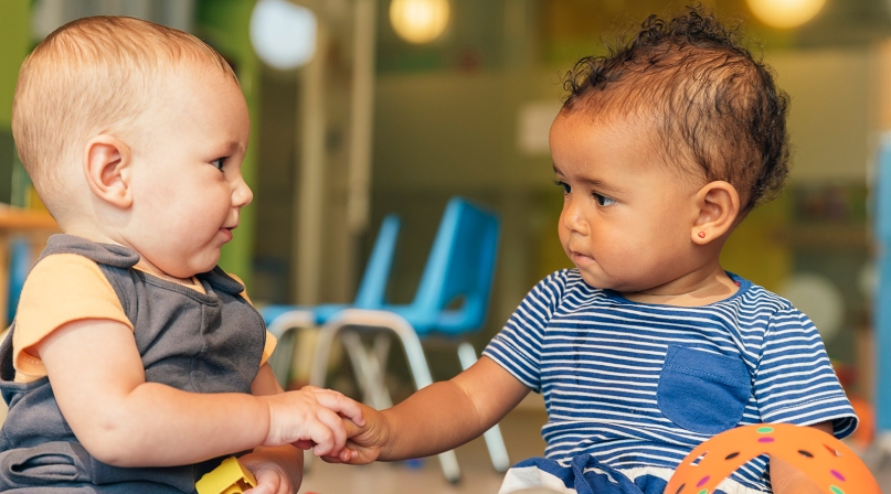 Image of Infants Playing and Holding Hands iStock Photo.jpg