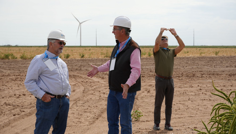 Carson County, Texas Judge Dan Looten (center) talks to Hodgeman County, Kan. Commissioner Mike Schraeder about wind power during a visit to the Panhandle Wind Project Development in Carson County. To the right, El Paso County, Texas Senior Policy Analyst Ramon Bracamontes take a photo of a nearby wind turbine. Photo by Charlie Ban