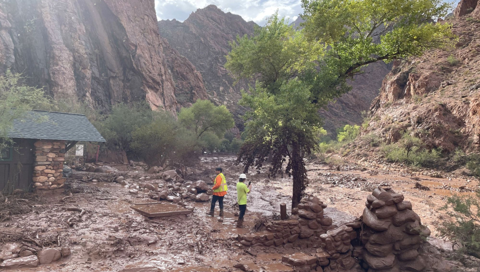 Two people stand among debris at near a footbridge that was destroyed in Grand Canyon National Park Aug. 29 during a flash flood earlier in the day. Photo courtesy of the National Park Service