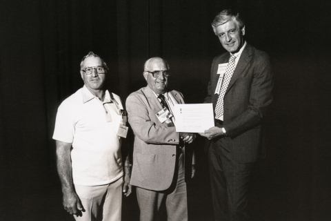 Executive Director Matt Coffey (right) hands an Achievement Award to Dougherty County, Ga. Commissioner Gil Barrett (center), a past NACo president, and a Doughtery County colleague.